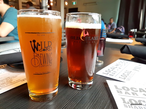 2 beverages from Local90, the left beverage is a light brown colour, the brown lager, and the right is a darker brown beer both in pint glasses.
