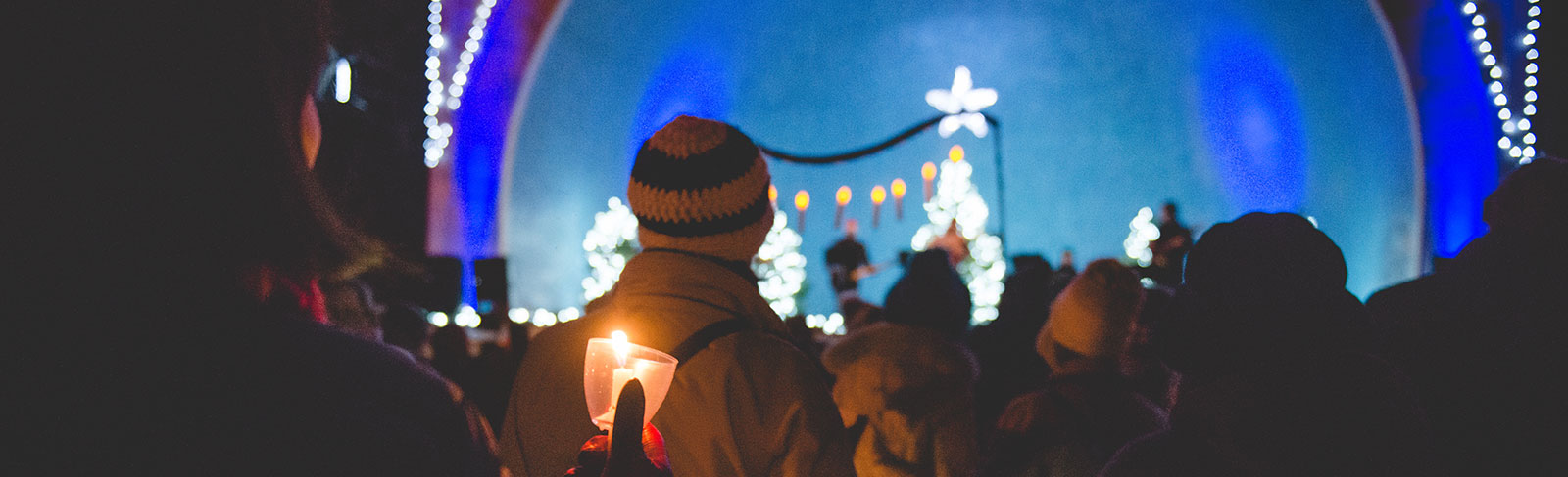 Woman holding candle watching band at the Candlelight Festival in Port Hope