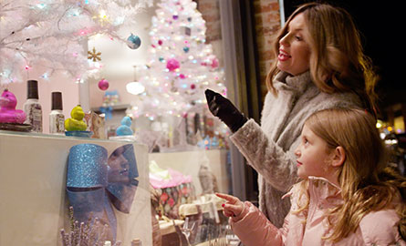 A mother and daughter looking at a Christmas tree in a shop window