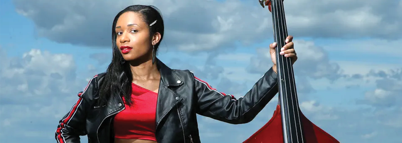 Image of woman holding a chello and looking towards the camera.