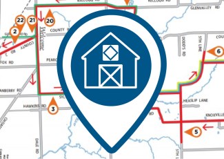 A pin icon of a barn with a quilt on it in front of a digital map.