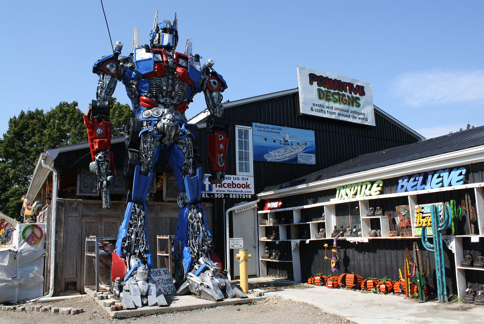 A large metal robot sculpture in front of a barn.