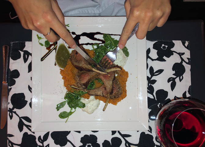 A guest cutting meat on a dinner plate from Hotel Carlyle
