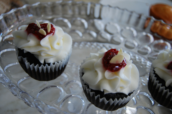 Two chocolate cupcakes with vanilla icing and raspberry jelly