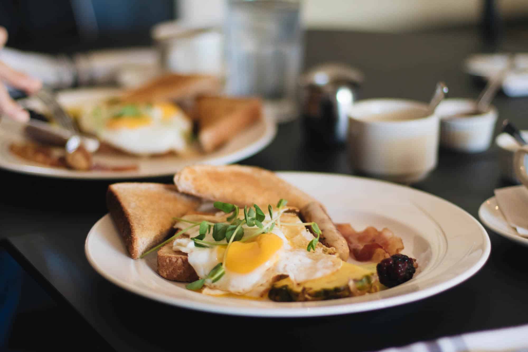 Two places of toast, eggs, bacon, and pineapple on the table at the Hotel Carlyle for breakfast.