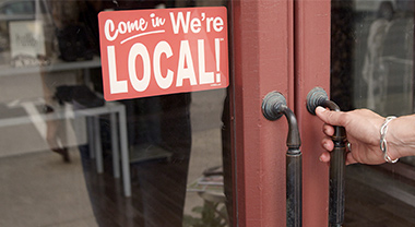 Person opening store door with local signage