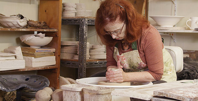 Artist working on pottery in her workshop