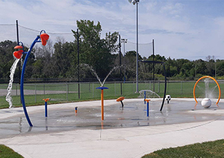 A splash pad water playground in a green park