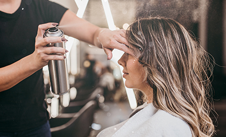 A hairdresser spraying hairspray on a customer.